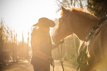 Wall Mural - Cowgirl with horse at sunset