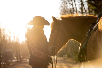 Wall Mural - Cowgirl with horse at sunset