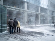 Natural disasters. People walk along the building through a blizzard with heavy snowfall. A snow cyclone covered the city.