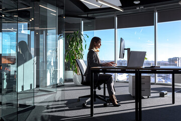 Female boss working at computer in office, silhouette of business woman sitting at desk successful and independent director