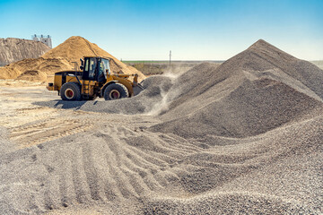 A large powerful loader overloads a pile of rubble in a concrete plant.