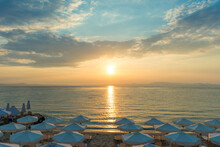 Beautiful Sunset Seascape With Beach Chairs And Umbrella On The Coast, Greece