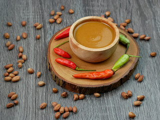 peanut sauce in a small wooden bowl on a gray wood texture background