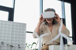 © LIGHTFIELD STUDIOS - Mature businesswoman in vr headset near models of buildings in office.