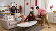 © PR Image Factory - smiling chinese mother watching television while father massaging her shoulders and adult children doing house chores in living room for new year. translation: spring and congratulations everyone
