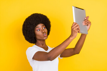 Wall Mural - Photo of happy nice positive dark skin lady make selfie tablet send air kiss isolated on yellow color background