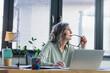 © LIGHTFIELD STUDIOS - Pensive businesswoman holding eyeglasses near laptop in office.