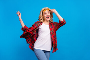 Wall Mural - Photo of adorable excited woman dressed checkered shirt glasses dancing looking empty space smiling isolated blue color background