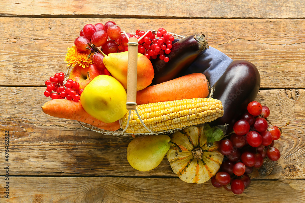 Basket with different healthy food on wooden background. Harvest festival