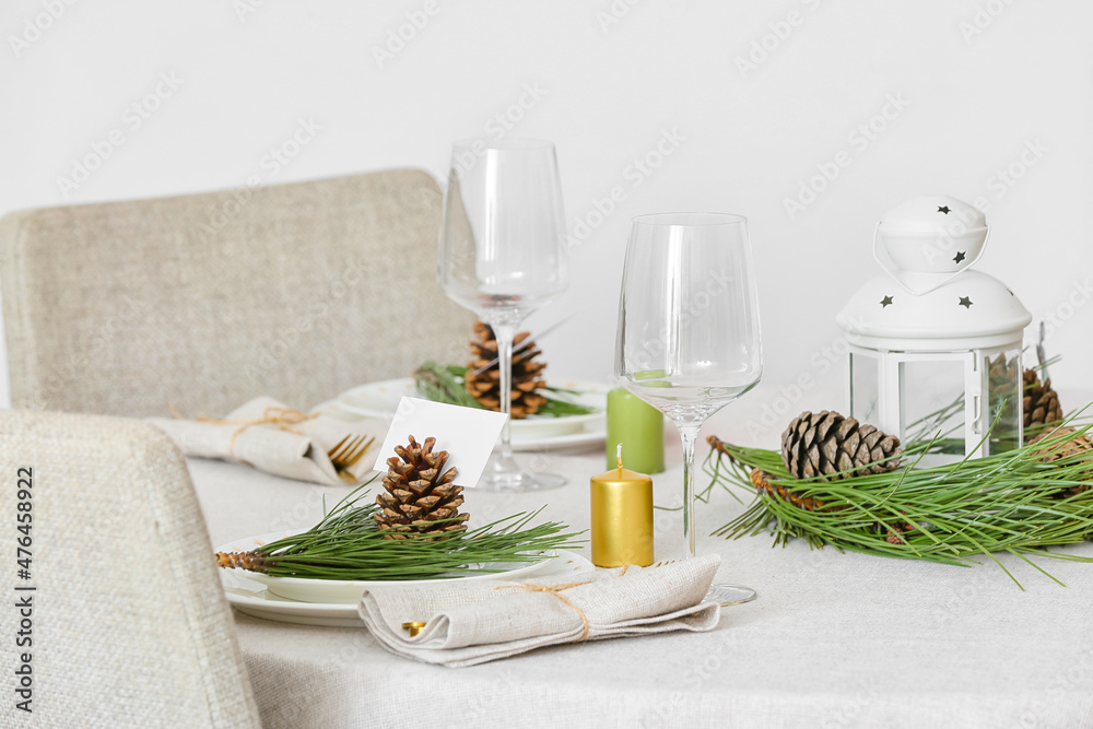 Beautiful table setting with pine cones and fir branches indoors