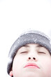 Teenager boy during a snowfall. Outdoors winter activities for kids. Cute child wearing a warm hat and closing his eyes