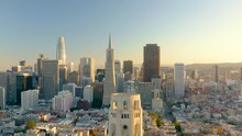 4K Aerial Video Footage Of San Francisco, California, At Sunset. Movement Is Backwards Over The Top Of Coit Tower, Buildings And Houses Lit By Setting Sun.