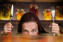 A Woman With A Knife And A Fork In Front Of A Table With An Empty Plate