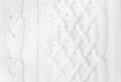 Soft knitted sweater texture closeup. Light abstract background. The trendy white backdrop for web design. Luxury twisted fabric backplate with patterns