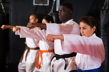 People practicing taekwondo and warming up for training while standing barefoot