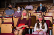 © JackF - mother and her daughter in maskas sitting at perfomance in theatrical auditorium