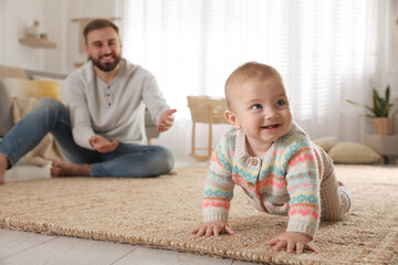 Poster - Happy young father watching his cute baby crawl on floor at home