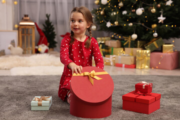 Poster - Cute little child with gift boxes near Christmas tree at home