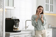 © New Africa - Young woman enjoying fresh aromatic coffee near modern machine in kitchen