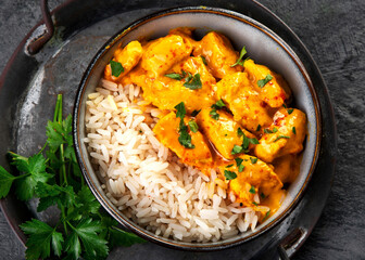 Wall Mural - Indian butter chicken curry with basmati rice on dark background.
