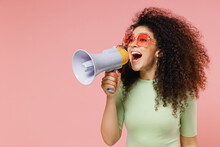 Exultant Happy Vivid Young Curly Latin Woman 20s Wear Mint T-shirt Sunglasses Hold Scream In Megaphone Announces Discounts Sale Hurry Up Isolated On Plain Pastel Light Pink Background Studio Portrait