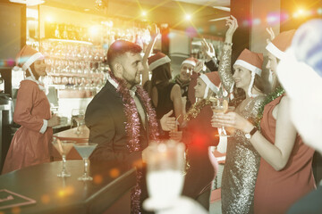 Wall Mural - Happy young man with female friends enjoying corporate new year party in bar