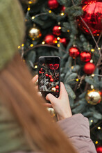 Woman Taking Pictures With Mobile Phone Of Christmas Tree Decorations