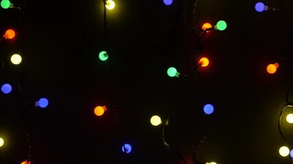Wall Mural - christmas, holidays and illumination concept - close up of electric garland lights in dark room