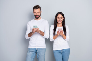 Photo of attractive funny sister brother wear white shirts chatting modern gadgets isolated grey color background