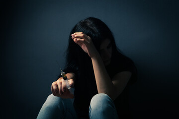 Wall Mural - Girl holding syringe with drugs while sitting on the floor