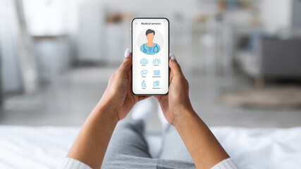 Woman laying on bed with mobile phone, using medical app