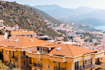 Houses and villas with red roofs in a resort town on mountain steep slope at the Mediterranean Sea. Real estate and urban development concept