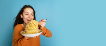 Excited Young Girl Preparing To Eat Large Portion Of Noodles Isolated On Blue Studio Background. World Pasta Day