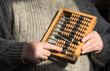 A woman in a knitted sweater holds wooden abacus in her hands. Concept accounting, vintage