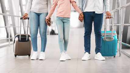 Wall Mural - Black family traveling together, holding hands in airport