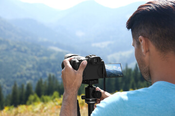 Sticker - Man taking photo of nature with modern camera on stand outdoors