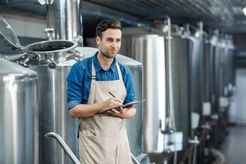 Wall Mural - Serious man using brewing equipment at factory. Control of plant, collect data