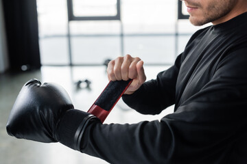 Wall Mural - Cropped view of man in sportswear wearing boxing glove in gym