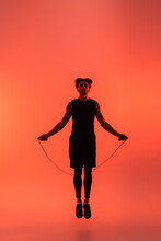 Sportsman Holding Skipping Rope While Jumping On Red Background