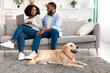 © Prostock-studio - Black couple at home using laptop sitting with dog