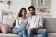 © Prostock-studio - Young muslim couple sitting on couch and looking at camera