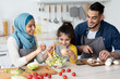 © Prostock-studio - Happy islamic family with little daughter preparing food together in kitchen