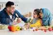 © Prostock-studio - Cheerful islamic parents having fun with little daughter while cooking in kitchen
