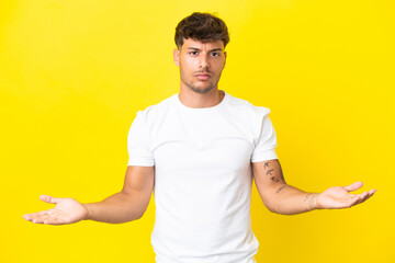 Sticker - Young caucasian handsome man isolated on yellow background having doubts