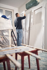 Wall Mural - Young adult man painting on a DIY budget renovation of his new home apartment.