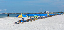 Couple Jogging In Front Of A Row Of Beach Chairs On Fort Myers Beach, Florida, USA.