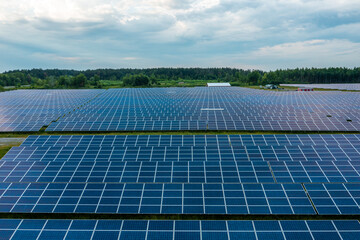 Huge solar power plant to use solar energy in a picturesque green field in Ukraine. Aerial panoramic drone shot