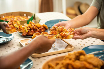 African family parents and two little daughter eating fried chicken and pizza on table for dinner together. Father and mother and cute child girl kid enjoy eating and sharing a meal together at home