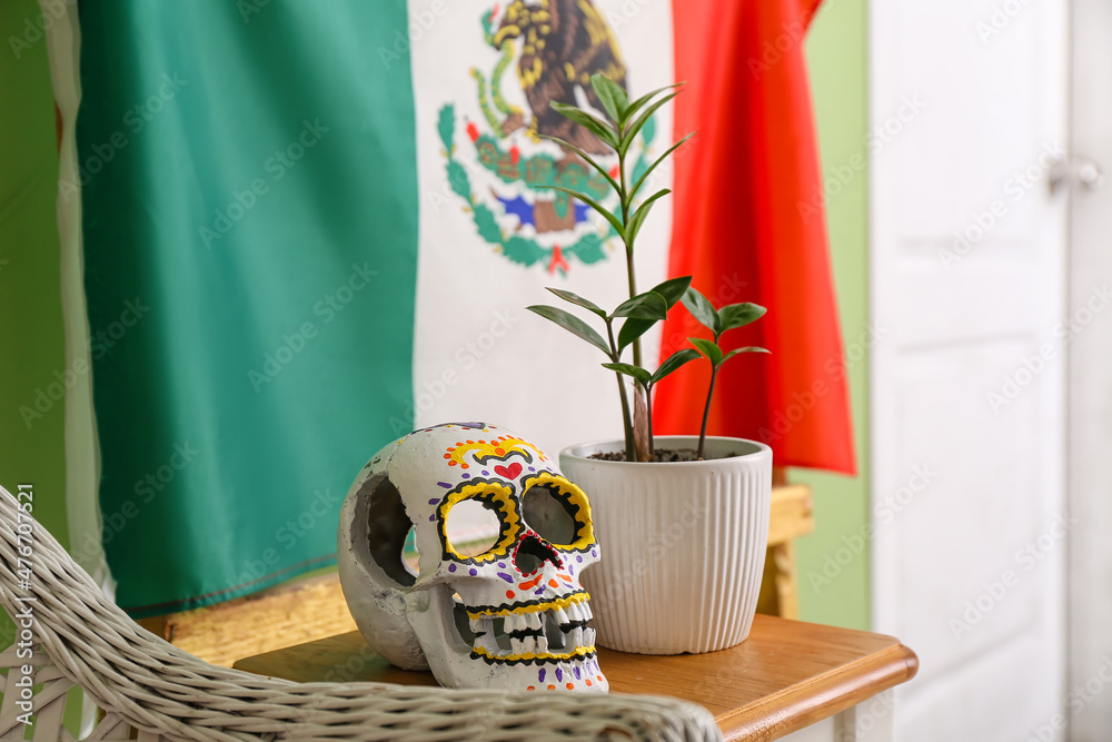 Human skull and flowerpot on table in room