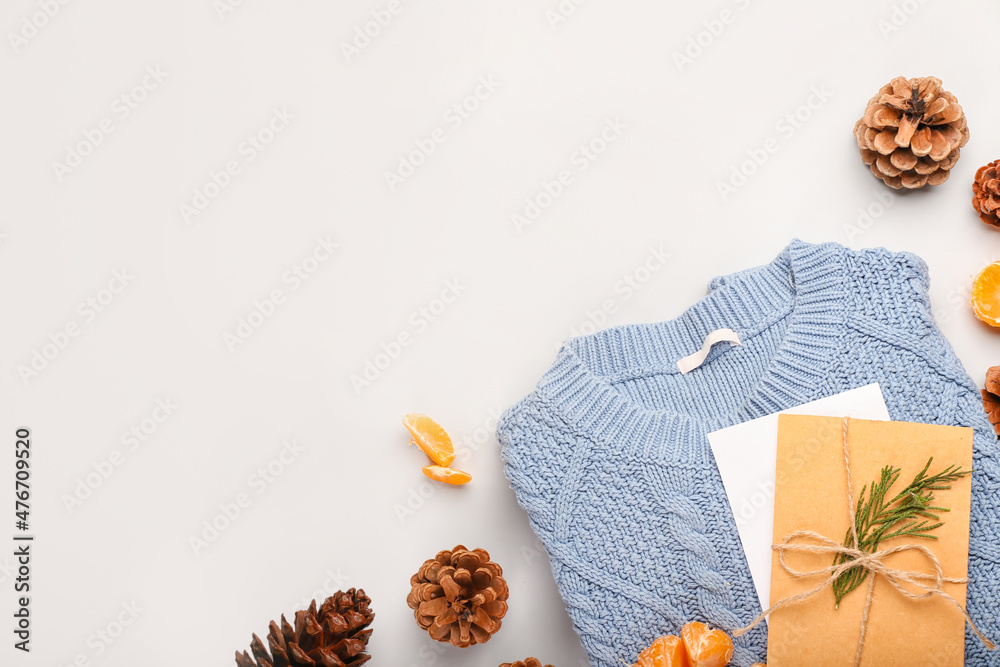Beautiful winter composition with sweater, card and cones on white background